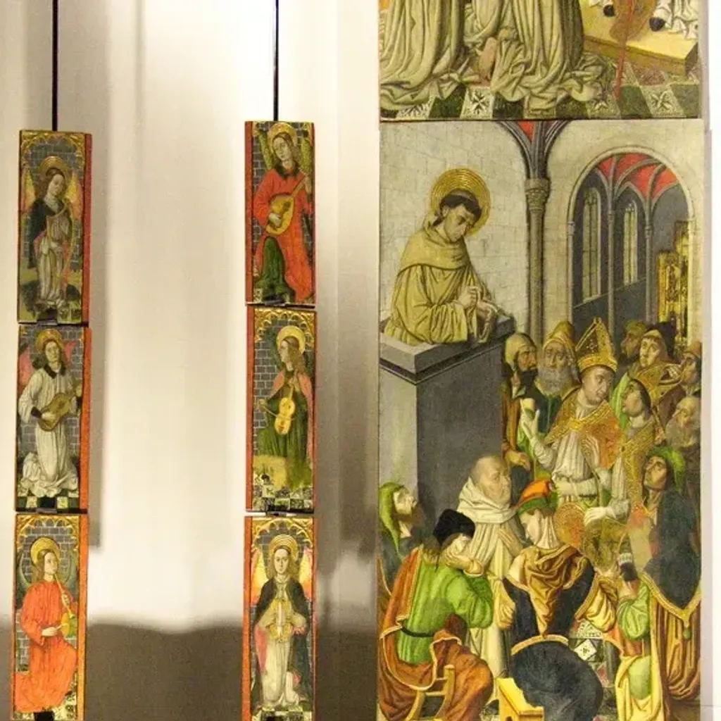 A photograph showcasing several historical panel paintings, likely religious art, displayed in a museum or gallery setting. The image features two vertical columns of smaller, individual painted panels on the left, and a larger, multi-figure panel painting on the right, which is partially cropped.