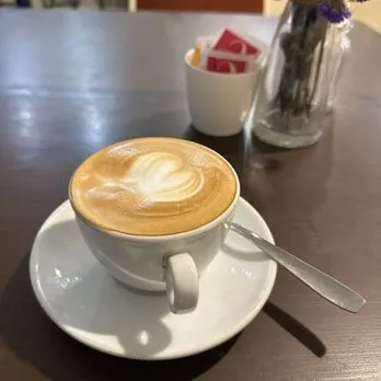 An inviting close-up of a latte with well-executed latte art, positioned on a table.