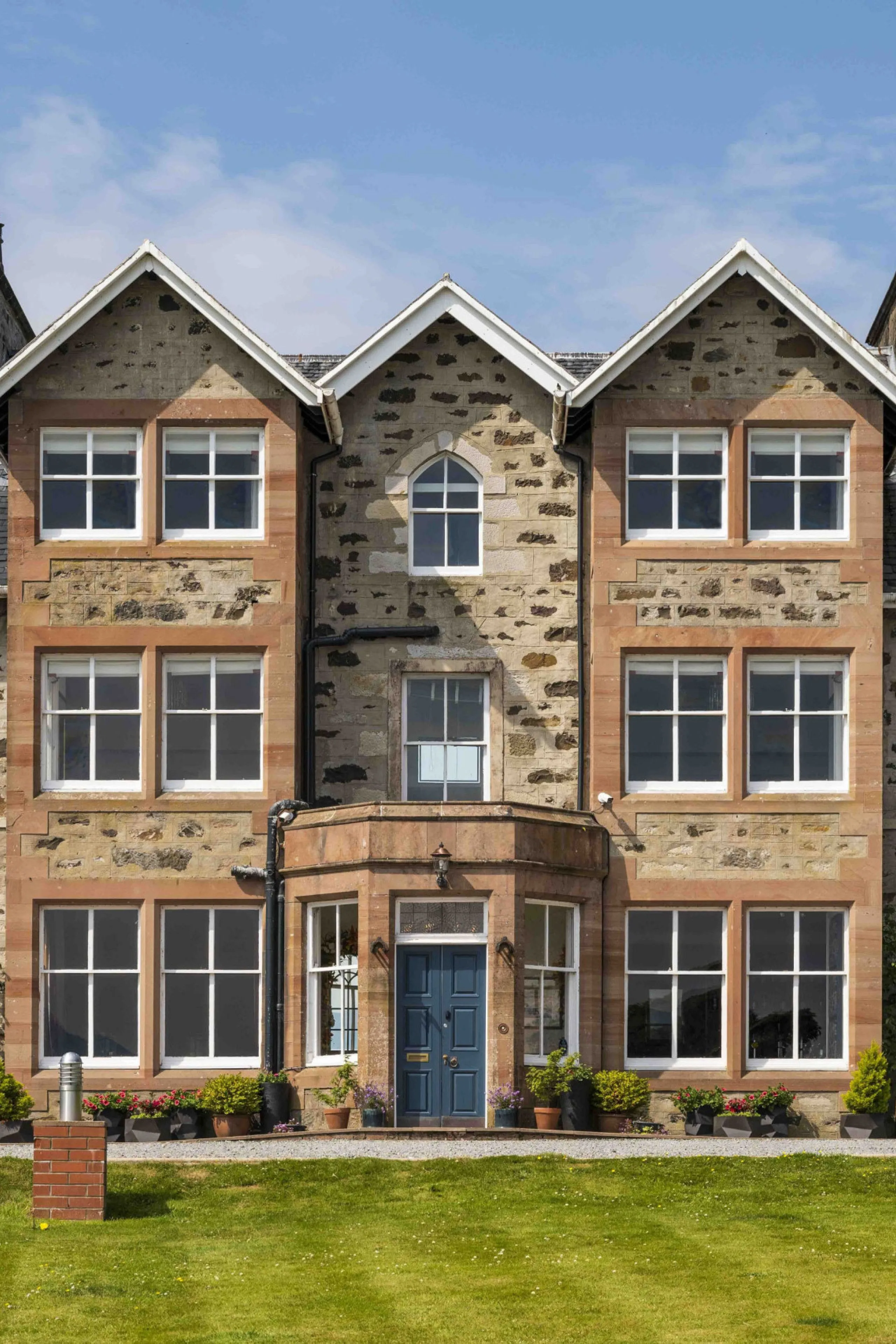 The image is exceptionally well-composed, centered, and clearly displays the building facade. It benefits from excellent and even lighting, free of harsh shadows or overexposure. The details of the stonework and window frames are remarkably sharp, contributing to a high degree of clarity. Colors appear natural and accurate, enhancing the photo-realistic quality of the image. All key elements are in perfect focus, making it a high-quality representation of the subject. No unwanted elements are present.