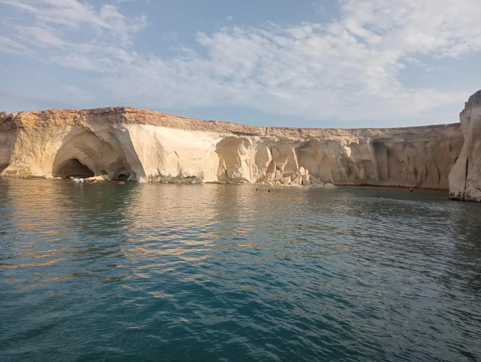 The image is photo-realistic with accurate colors, showcasing a natural landscape of sea cliffs. Key elements are in focus and the lighting is generally good, effectively illuminating the scene. The composition is adequate, providing a clear view of the subject. Some areas of the cliffs might appear slightly flat due to direct overhead lighting.