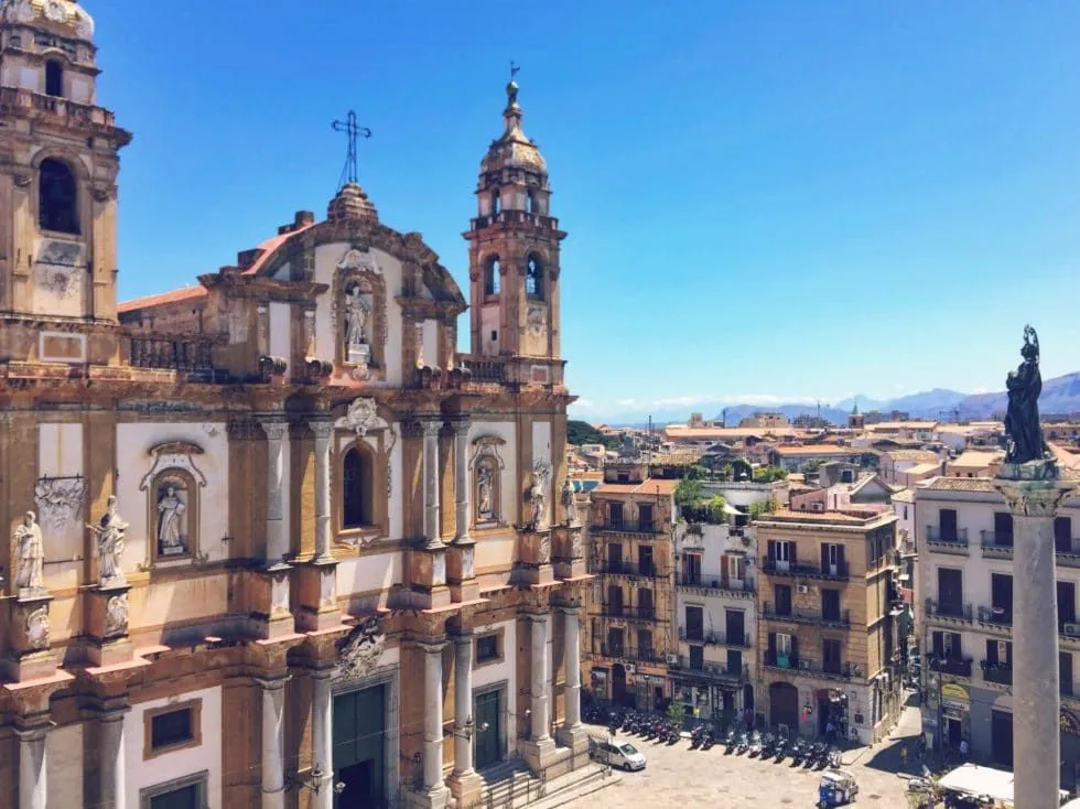 An aerial or elevated view of a historic church and surrounding cityscape under a clear blue sky.