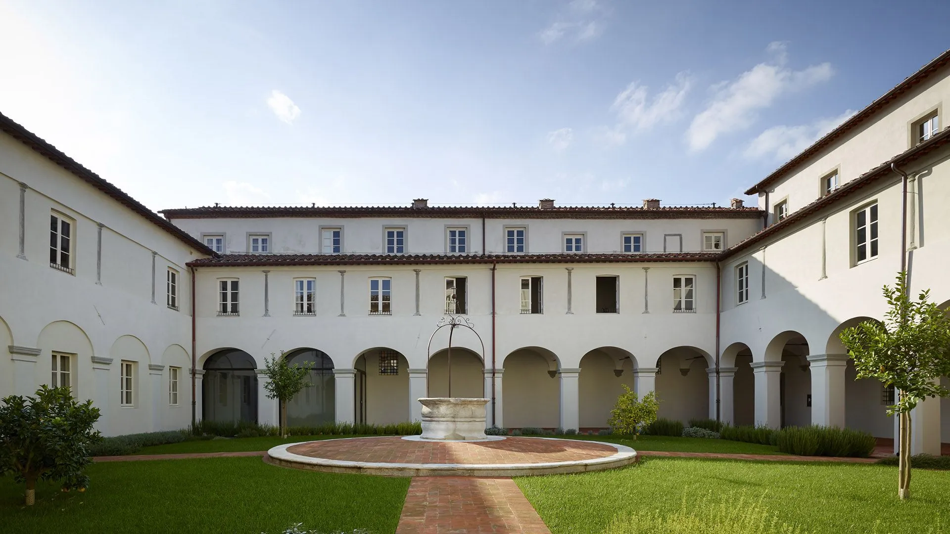 A well-composed and well-lit image of a traditional courtyard with a central well, surrounded by a symmetrical building with arches. The image is sharp, color-accurate, and highly photo-realistic, with all key elements in focus.