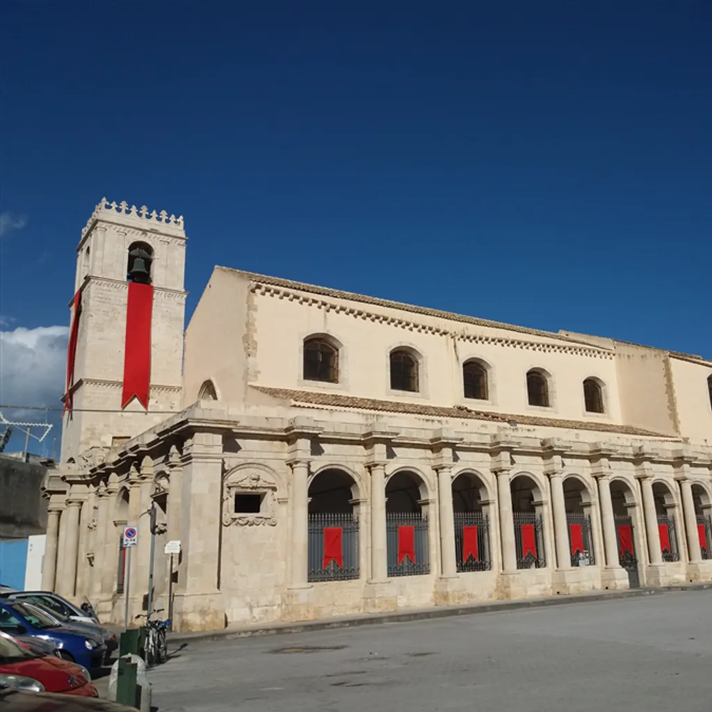 The image features a historical building under a clear blue sky, demonstrating good natural lighting and sharp architectural details. Colors appear accurate and the image is photo-realistic, with the main subject clearly in focus. While the composition is decent, it includes a large expanse of empty sky and minor distracting elements like a bicycle and street sign, which slightly detract from an otherwise strong visual.