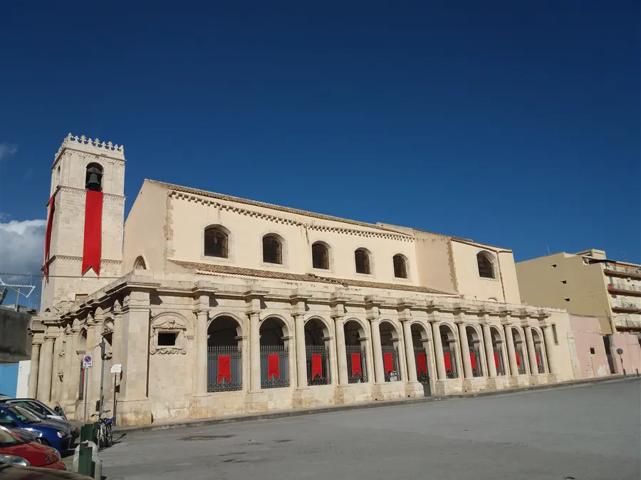 The image features a historical building under a clear blue sky, demonstrating good natural lighting and sharp architectural details. Colors appear accurate and the image is photo-realistic, with the main subject clearly in focus. While the composition is decent, it includes a large expanse of empty sky and minor distracting elements like a bicycle and street sign, which slightly detract from an otherwise strong visual.