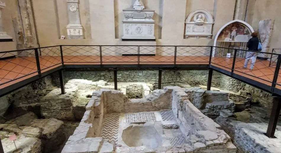 The image effectively captures an archaeological excavation with good sharpness and photo-realism, ensuring that the ruins and the modern walkway are in clear focus. The composition provides a comprehensive view of the multi-layered historical site. However, the lighting is somewhat dim, leading to a slightly subdued appearance, and the overall composition could be marginally improved to eliminate the slight cutoff on the right side of the frame.