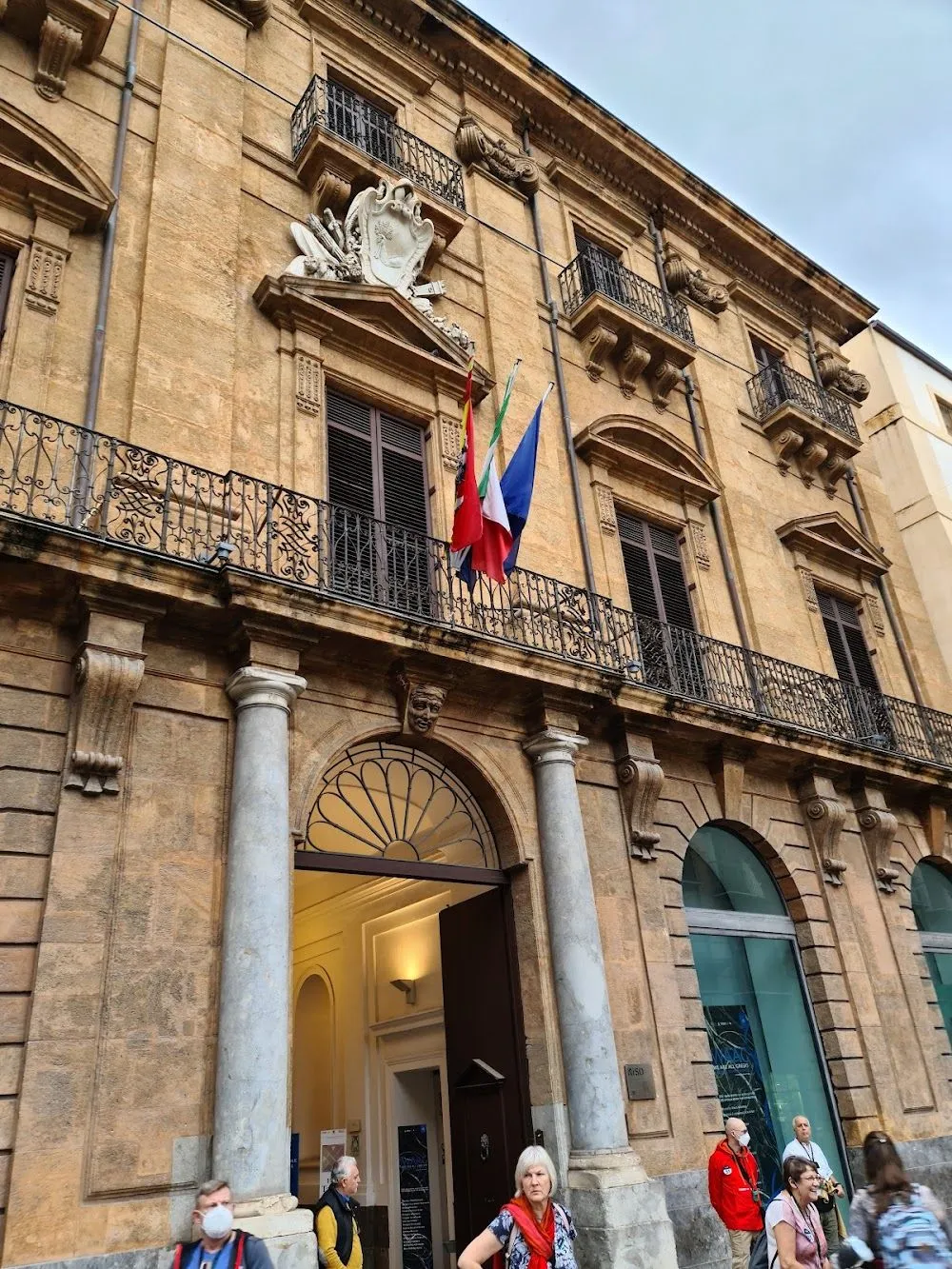 The image is photo-realistic with accurate colors and the key architectural elements, including the building facade, balconies, and flags, are in focus and appear sharp. The composition effectively captures the building. However, the lighting is somewhat flat due to what appears to be an overcast day, which reduces dynamic range and depth compared to more dramatic lighting.