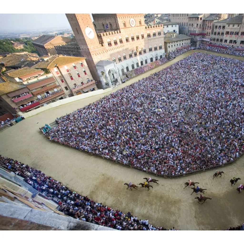 This image captures the excitement of the Palio di Siena from an aerial perspective, providing a comprehensive view of the horse race, the massive crowd, and the historic Piazza del Campo. The natural lighting is excellent, contributing to vibrant and accurate colors. Key elements like the horses and the track are sharp, and the overall photo-realism is high, effectively conveying the scale and atmosphere of the event.