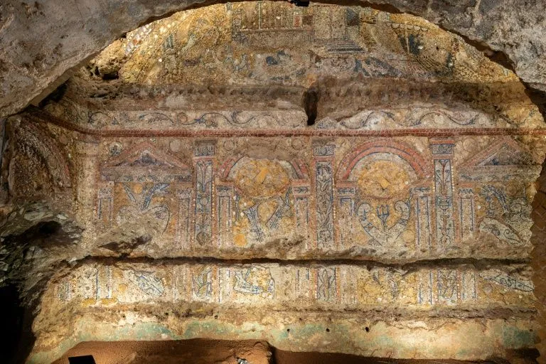 An excellent photograph of ancient mural art within what appears to be a tomb or cave. The image is highly photo-realistic, sharp, and the key elements of the artwork are entirely in focus. The composition effectively frames the intricate details of the ancient painting, and the colors appear accurate for aged pigments on a stone surface.