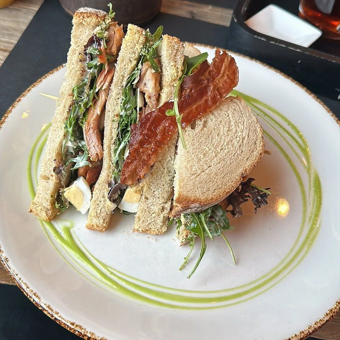 A well-composed and sharply focused image of a delicious-looking sandwich. The natural lighting highlights the textures and colors of the ingredients, making them appear fresh and appetizing. The blurred background ensures the sandwich remains the clear focal point.