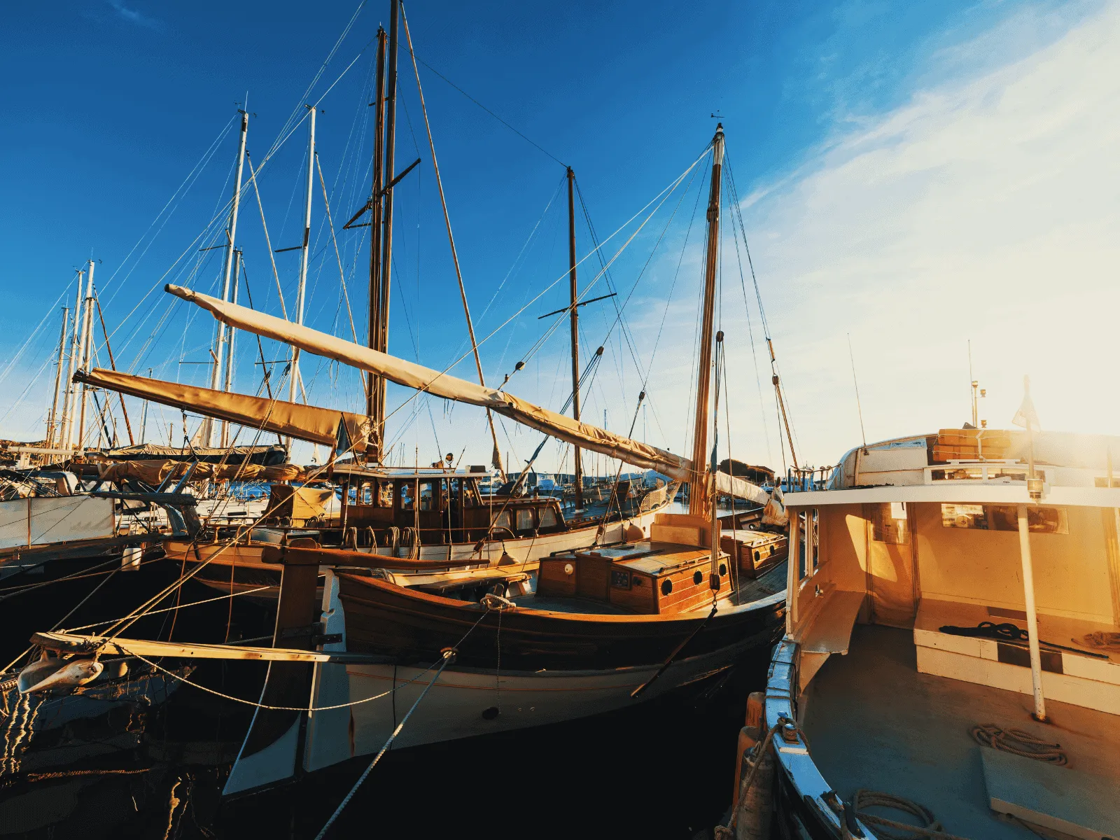 A vibrant image showcasing several sailboats docked in a bustling marina under a clear, bright blue sky.