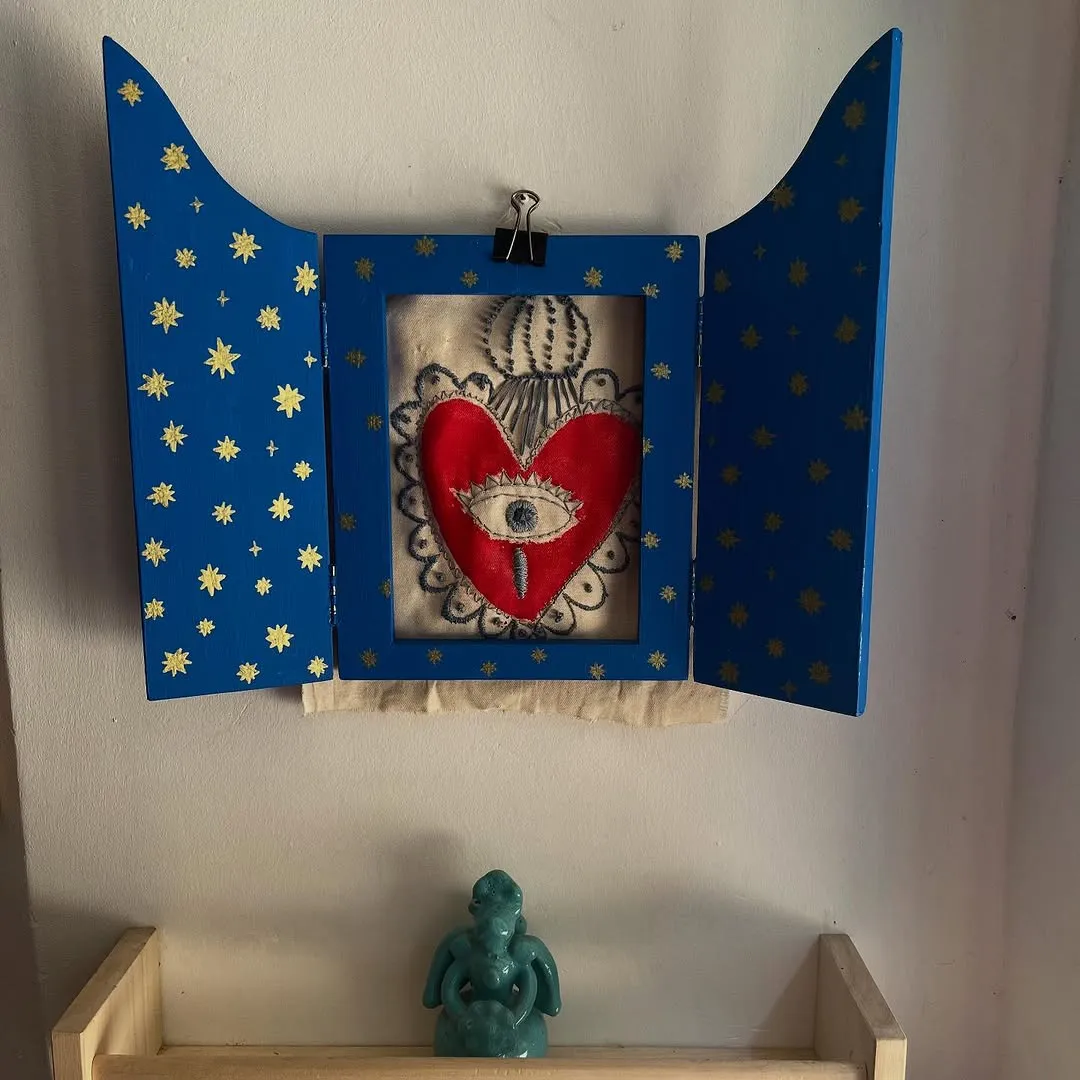 The image prominently features a framed heart art piece which is the clear focal point and is sharply rendered. The composition is generally good, centering the main subject. The lighting, however, is somewhat uneven, causing some areas below the art piece to appear a bit underexposed. The colors are reasonably accurate, and the image is photo-realistic, capturing the physical object well.