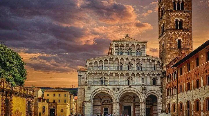 The image prominently features an ornate historical building, likely a church, under a dramatic, colorful sky at what appears to be sunset. The composition effectively highlights the architectural details of the building, which is well-centered and fills a significant portion of the frame. The sky contributes significantly to the mood and visual appeal.