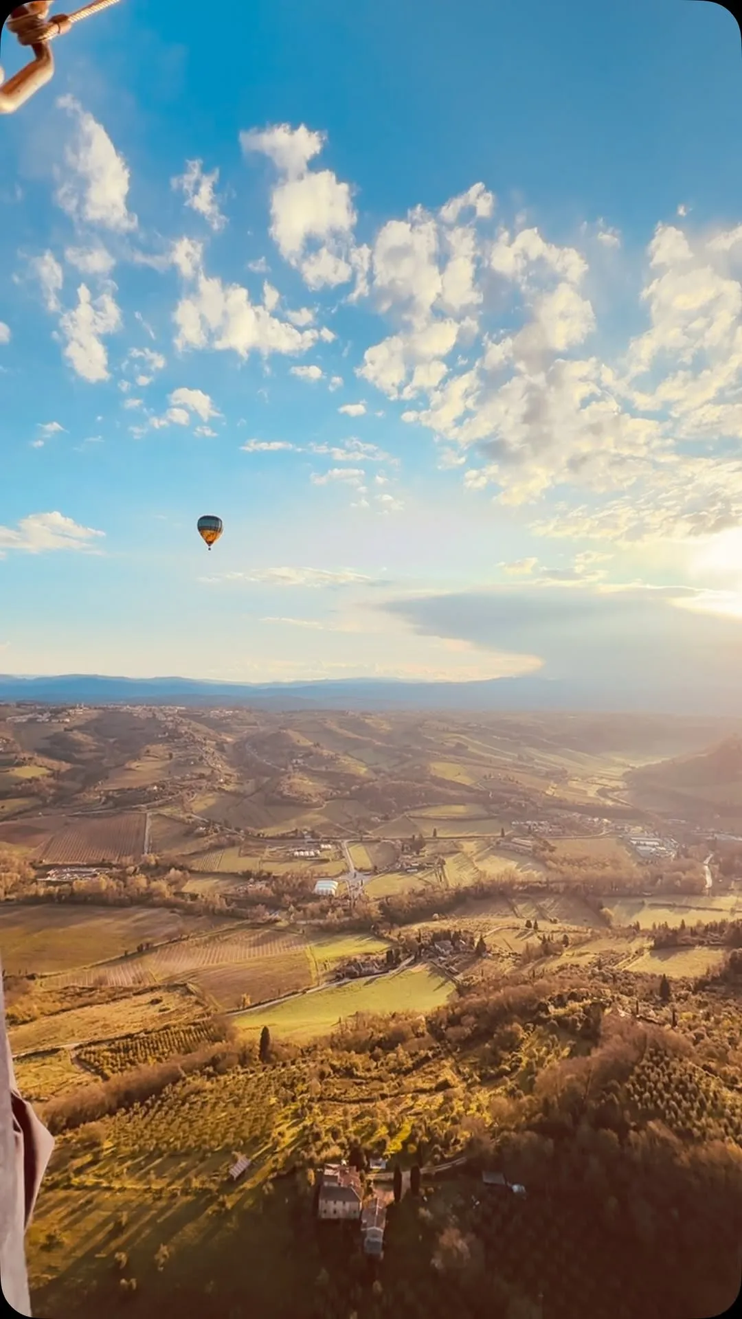 The image is very well-composed, featuring a hot air balloon against a beautiful sky and a vast landscape during golden hour. The lighting is excellent, providing warm tones, although there is a slight sun glare on the right side. The image is sharp and highly photo-realistic, with the key elements, especially the hot air balloon, clearly in focus. Colors appear natural and vibrant for the lighting conditions.