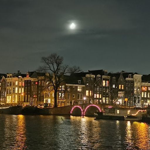 This image is an example of exterior photography. It shows a cityscape at night with a canal, buildings, and reflections. The composition is well-balanced, and the photographer has used the leading lines of the canal and the buildings to create a sense of depth. The image is well-lit, and the photographer has used the different light sources to create a warm and inviting atmosphere. The colors are accurate, and the image is sharp. There are no unwanted elements in the image. Based on the above criteria: - The image successfully captures the beauty of the night cityscape. - The photographer has used light and composition effectively to create a visually appealing image. Score: 95 Strengths: - Well-composed and well-lit - Accurate colors and sharpness - No unwanted elements Weaknesses: - None
