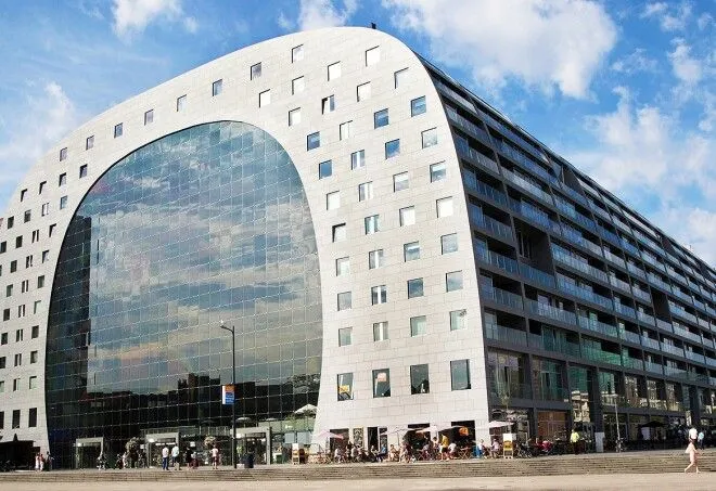 The image captures a modern architectural building with excellent clarity and vibrant, true-to-life colors. The composition is strong, highlighting the unique curved facade and reflective glass, and the entire scene is well-lit under bright daylight conditions. The sharpness is impressive, with all key elements of the building in clear focus, contributing to a highly photo-realistic appearance.