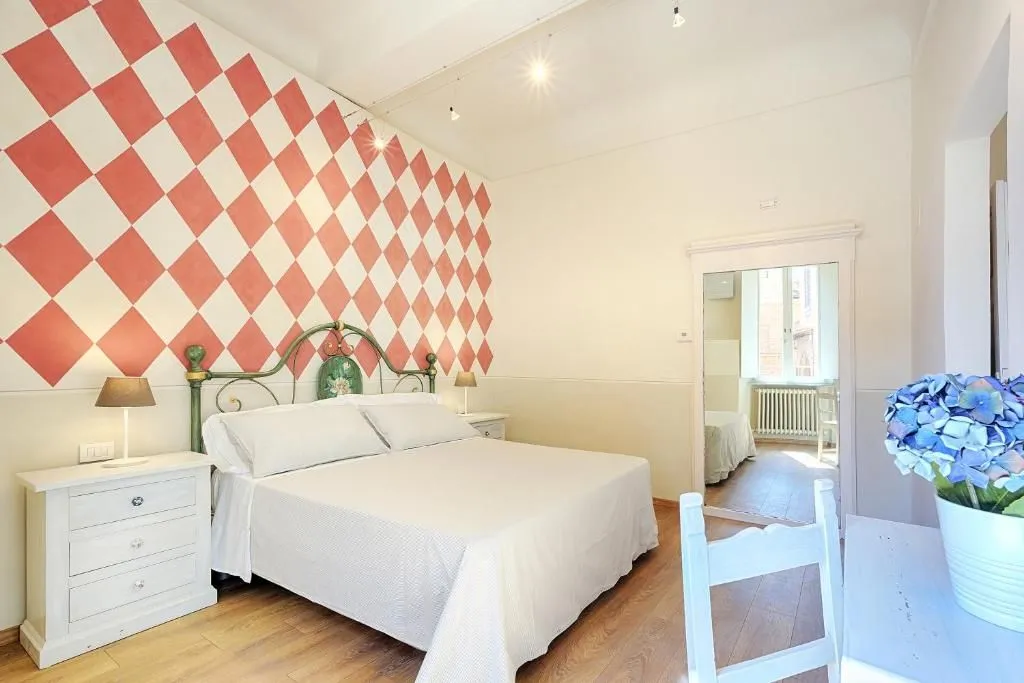 The image effectively captures a bedroom interior, showcasing good sharpness, color accuracy, and photo-realism. Key elements like the bed and the distinctive patterned wall are in clear focus. While the lighting is generally good, providing ample illumination, there is some minor glare from the ceiling light fixtures. The composition is decent, though the partially visible chair in the foreground could be re-framed for better overall balance.