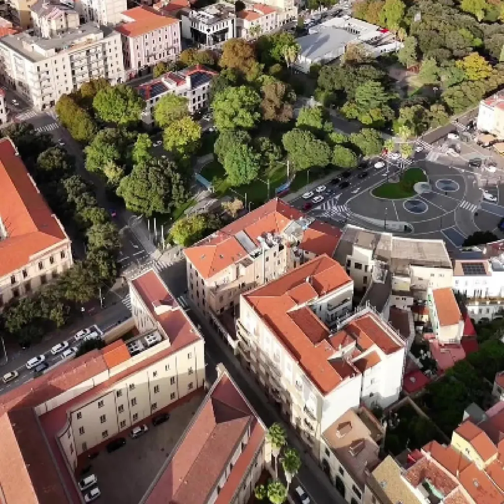 An aerial photograph capturing a dense urban area with a significant central park and surrounding buildings, along with roads and vehicles. The image is taken during daylight, showing clear skies and natural light.