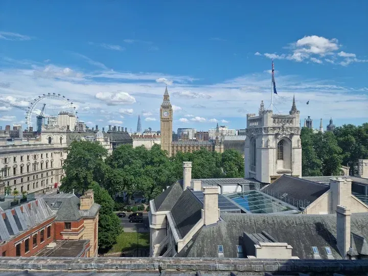 The image offers a well-composed and vibrant editorial view of the London skyline, with Big Ben as a prominent feature against a clear blue sky. The lighting is natural and even, contributing to accurate colors and a high degree of photo-realism. Key elements like Big Ben and the surrounding architecture are sharp and in focus, creating a clear and engaging perspective of the city.