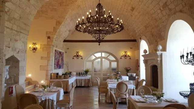An inviting interior shot of a restaurant, featuring an ornate chandelier, arched ceilings, and set tables, suggesting an elegant dining experience.