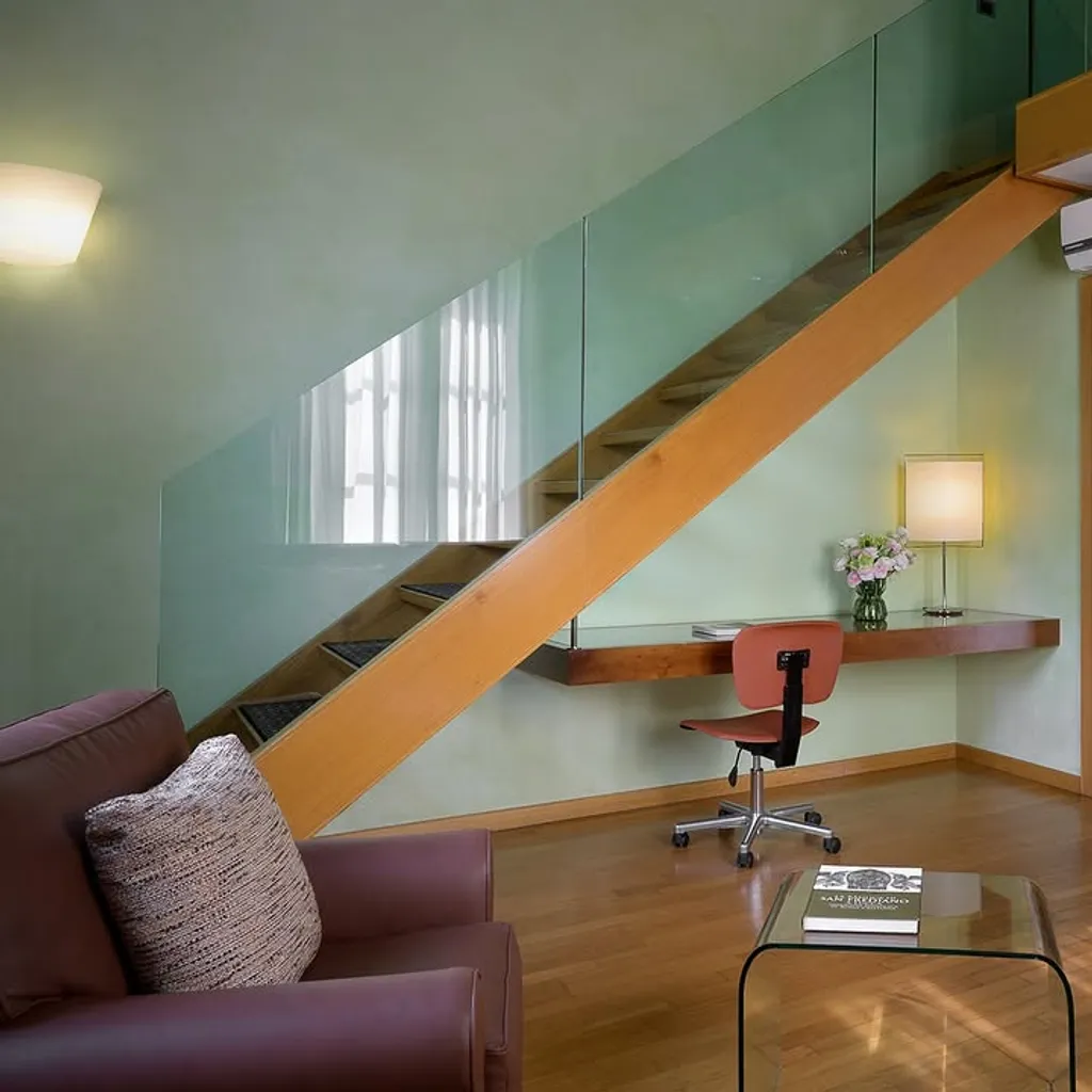A well-composed and sharply focused image of a modern interior space, likely a hotel room or apartment, featuring a wooden staircase with a glass railing, a study desk area with a chair, and part of a living area. The lighting is good, and colors appear natural and accurate.