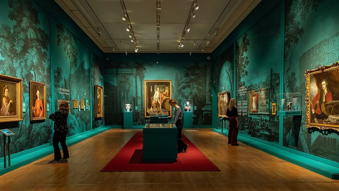 The image showcases a well-composed and aesthetically pleasing museum interior. The lighting is effective in highlighting the exhibits and creating a distinct atmosphere. The photograph is sharp, photo-realistic, and features vibrant, color-accurate tones. All key elements, including the art pieces, display cases, and visitors, are in clear focus.