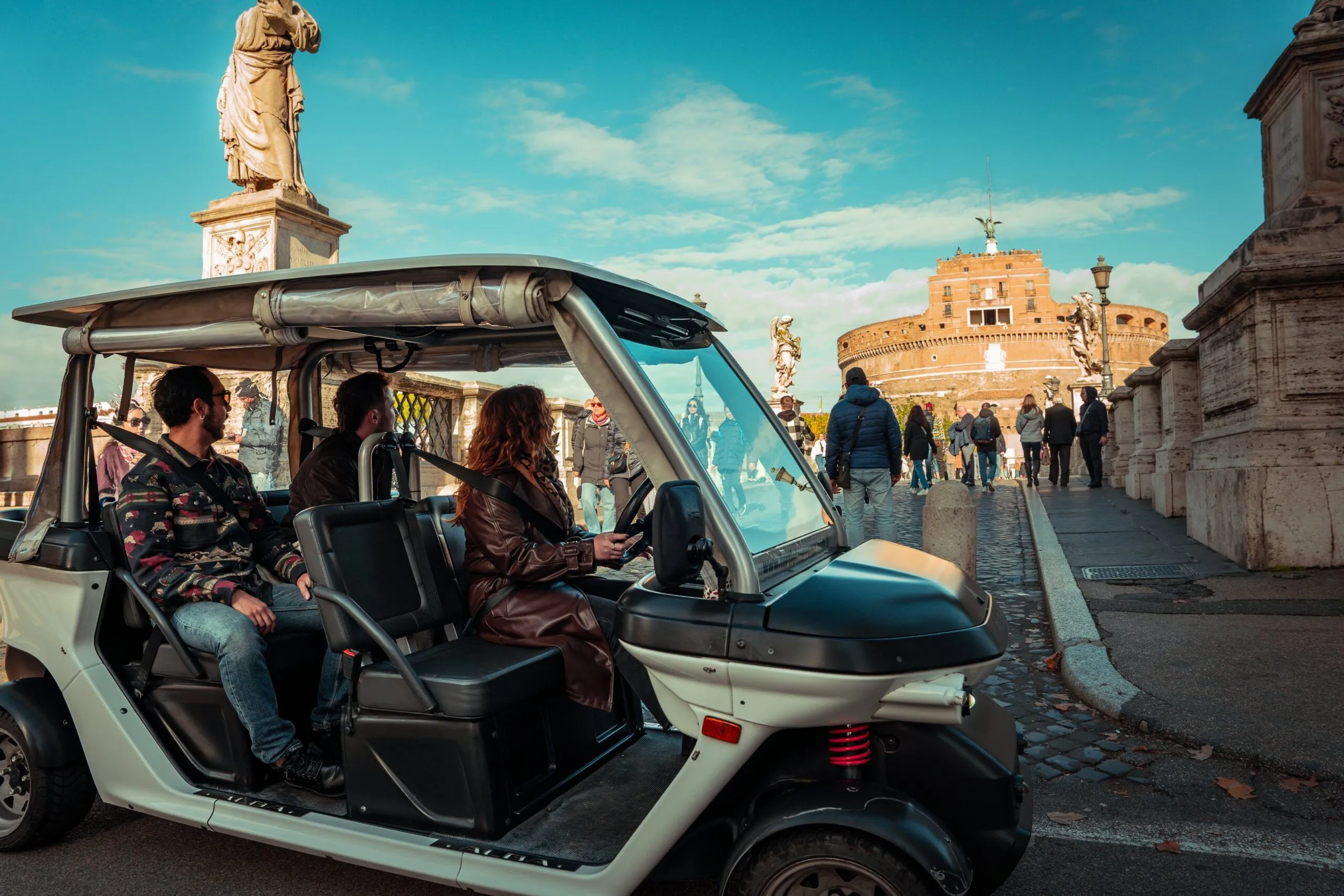 The image captures an urban scene featuring a golf cart with people in the foreground and a historic building in the background under clear skies.