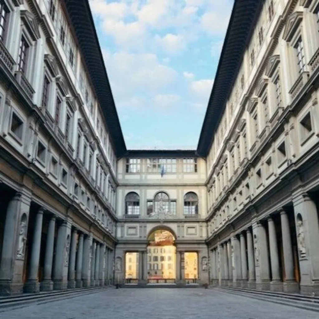 A well-composed editorial image of a grand, symmetrical architectural courtyard, possibly the Uffizi Gallery, featuring classical buildings with numerous windows and columns under a bright sky.