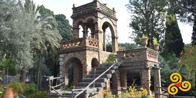 An image featuring an old brick and stone structure with arches and steps, set within a natural, garden-like environment.