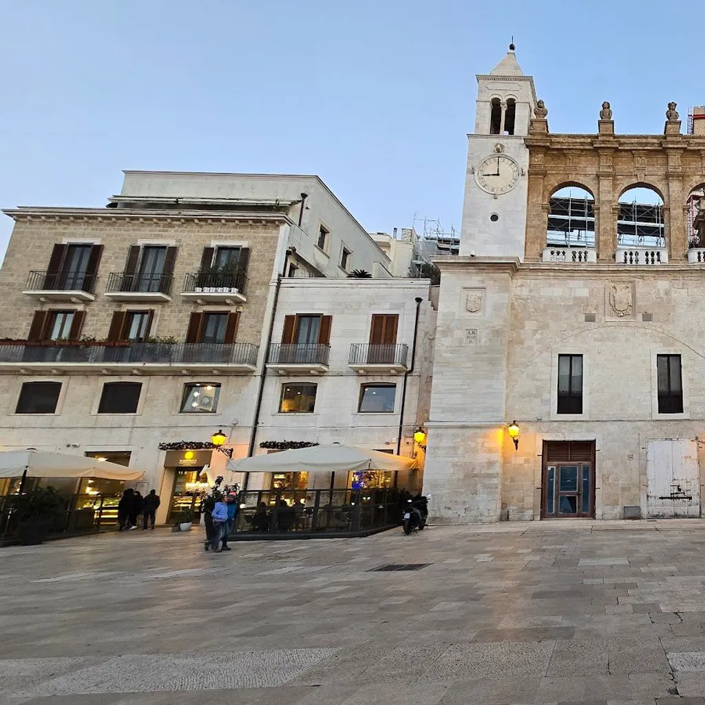 The image is sharp and photo-realistic, with natural colors and well-focused architectural elements. However, the composition could be improved as the foreground contains distracting elements such as scooters and outdoor seating. The lighting is even but lacks dynamic range, and reflections in the archway could be considered a minor distraction.