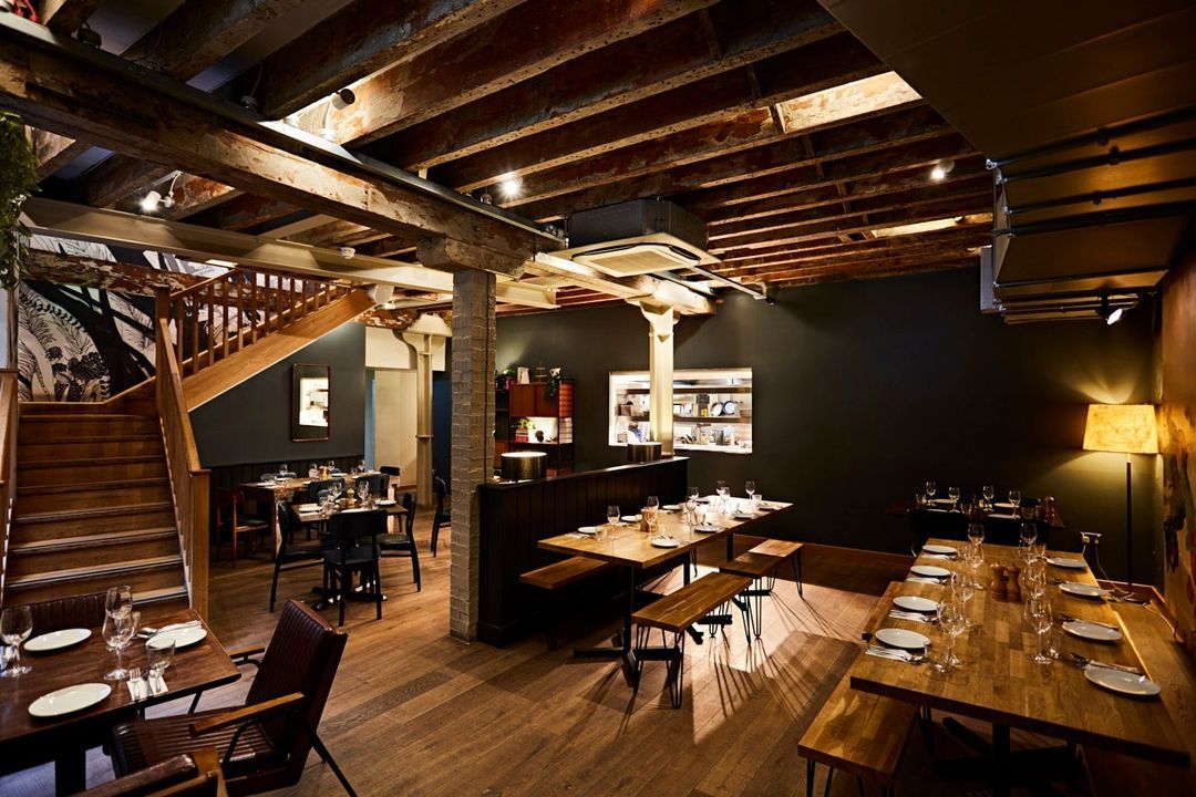 This image showcases a well-composed and well-lit interior shot of a restaurant. The composition is balanced, drawing the viewer's eye to the center of the image where the tables are set. The lighting is warm and inviting, highlighting the rustic and industrial elements of the space. The exposed beams, brick walls, and wooden furniture create a visually appealing and authentic ambiance. The image is sharp, capturing fine details like the texture of the wood and the intricate patterns on the walls. The colors are accurate, with a slightly warm tone that enhances the overall mood. The key elements, including the tables, chairs, and lighting fixtures, are in focus. While the image contains empty tables and chairs, it does not include any unwanted elements like cluttered environments or half-eaten food. The image effectively conveys the atmosphere and design of the restaurant.
Score: 85
Strengths:
- Well-composed and balanced shot.
- Warm and inviting lighting.
- Sharp and detailed image.
- Color-accurate and visually appealing.
- Key elements are in focus.
Weaknesses:
- No significant weaknesses.
