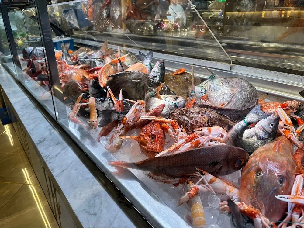 An editorial image showcasing a variety of fresh fish and seafood on ice in a display case.