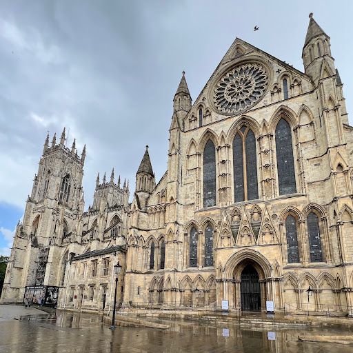 This image captures the impressive exterior of York Minster. The composition is well-balanced, showcasing the cathedral's grandeur and intricate details. The lighting is adequate, providing a good balance between the bright sky and the shadowed areas of the building. The image is sharp, revealing the intricate carvings and textures of the stonework. The color accuracy is good, with natural tones and subtle variations in the stone. The key elements, such as the windows, doorways, and overall structure, are in focus. The image is photo-realistic, accurately representing the cathedral's appearance. Overall, the image is well-composed and visually appealing, effectively conveying the architectural beauty of York Minster.