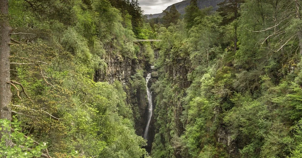 A beautiful and well-composed image of a waterfall cascading through a lush, green gorge. The natural lighting provides good visibility of details in the rocks and foliage.