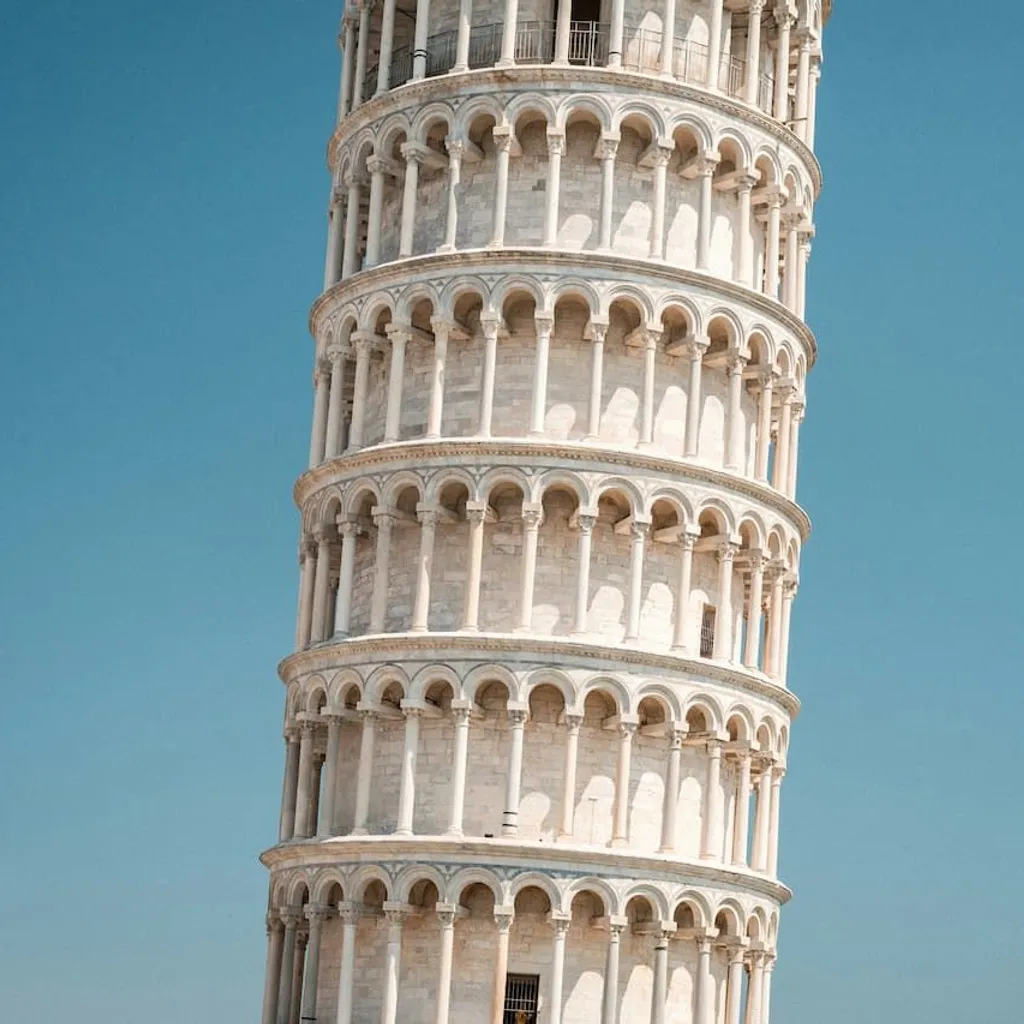The image prominently features the Leaning Tower of Pisa against a clear blue sky, showcasing its iconic tilt and intricate architectural details. The composition is strong, focusing entirely on the tower without distractions, and the lighting is bright and even, highlighting the texture of the stone.
