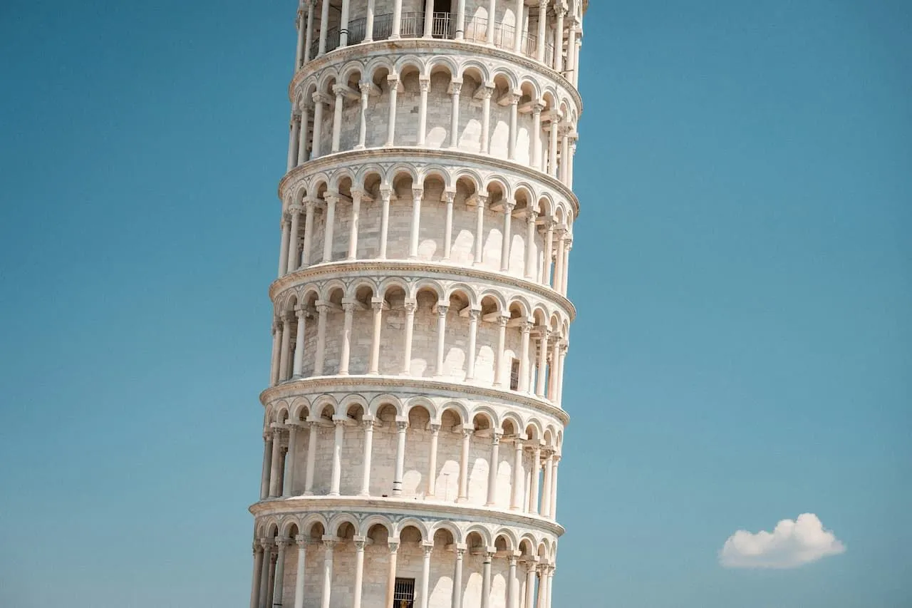 The image prominently features the Leaning Tower of Pisa against a clear blue sky, showcasing its iconic tilt and intricate architectural details. The composition is strong, focusing entirely on the tower without distractions, and the lighting is bright and even, highlighting the texture of the stone.