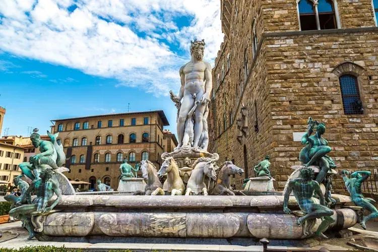A well-composed and vibrant photograph of the Fountain of Neptune in Florence, Italy, showcasing the intricate details of the sculptures and the surrounding historic architecture under a bright, clear sky.