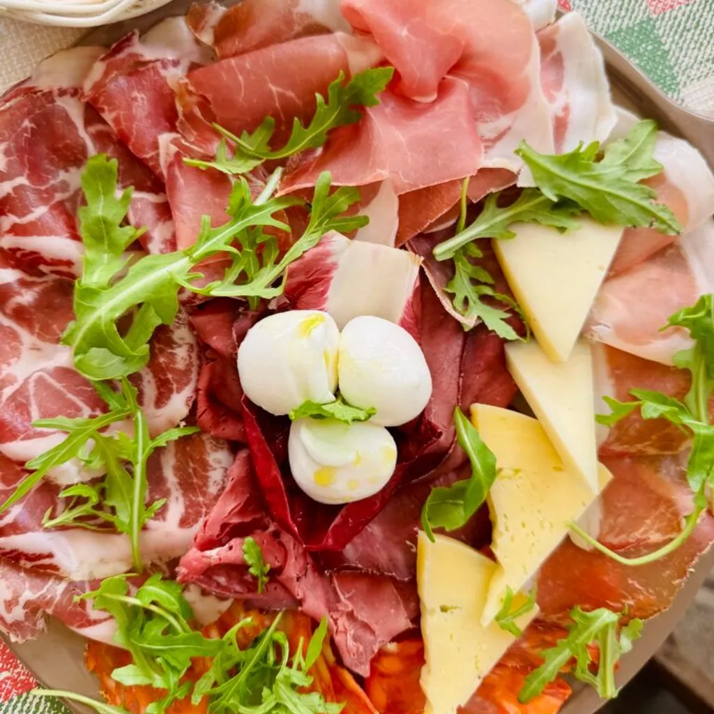 An overhead shot of a well-arranged charcuterie board featuring a variety of cured meats, cheeses, and fresh arugula.