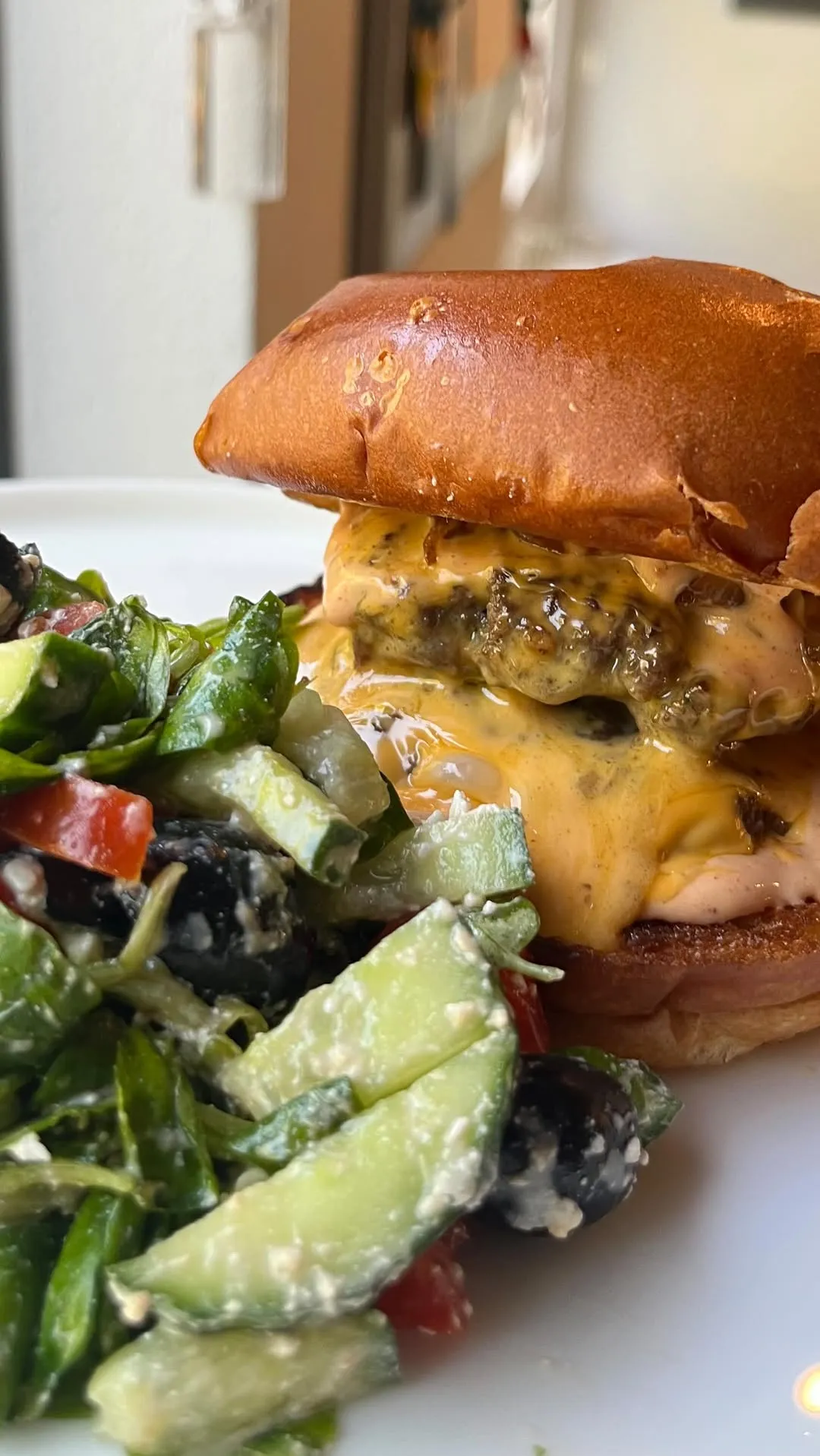 A close-up, appetizing shot of a burger with melted cheese alongside a fresh salad. The composition focuses on the food, showcasing its textures and vibrant colors. The lighting is even, and the key elements are sharp and in focus.