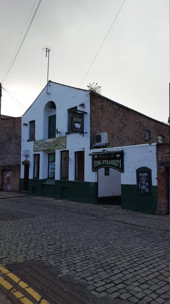 This is a photo-realistic and sharp image of a pub exterior, with the building clearly in focus and occupying a good portion of the frame. The colors appear natural, however, the overall lighting is somewhat flat and dim, which detracts slightly from the vibrancy and impact of the image. The composition is generally well-executed, showcasing the pub effectively.
