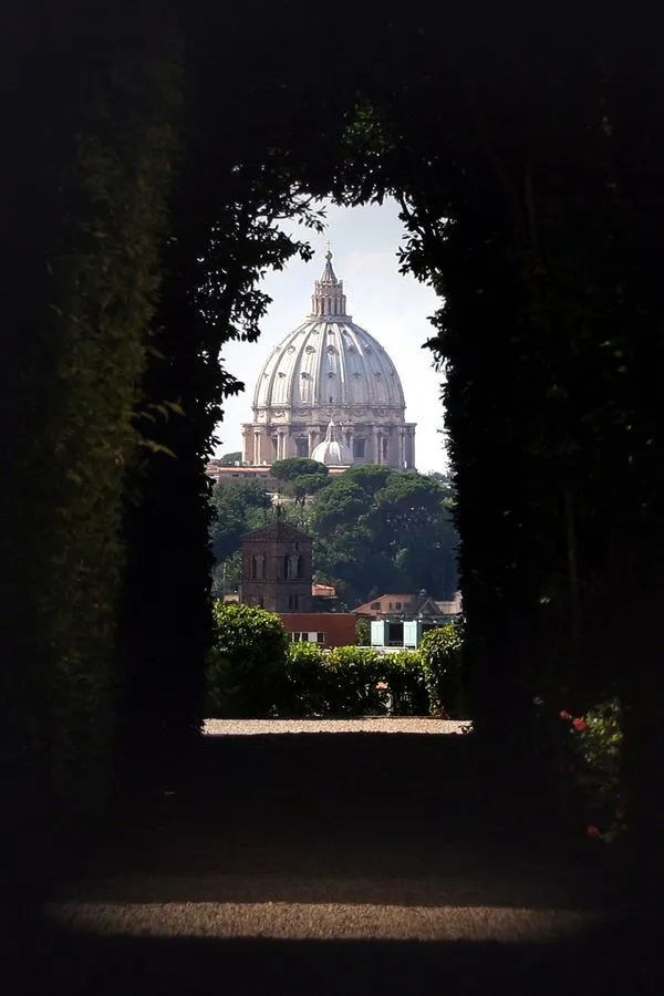 A well-composed image featuring an iconic architectural dome framed by dark foliage, characteristic of a view through a natural archway.