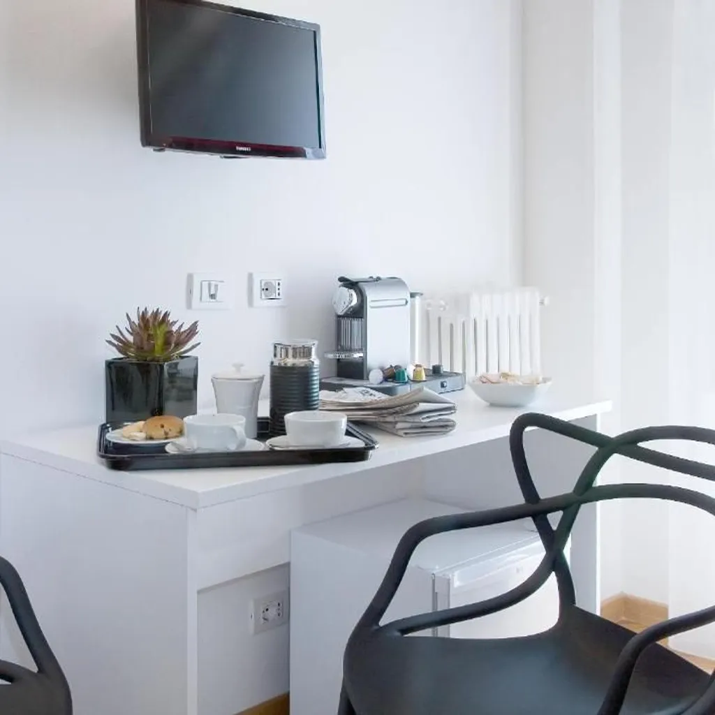 The image is well-composed, clearly showcasing a modern coffee station and amenities in what appears to be a hotel room or suite. The lighting is even and natural, contributing to good color accuracy and a clean aesthetic. All key elements, including the coffee machine, cups on the tray, and plant, are in sharp focus, making the image highly photo-realistic and professional.