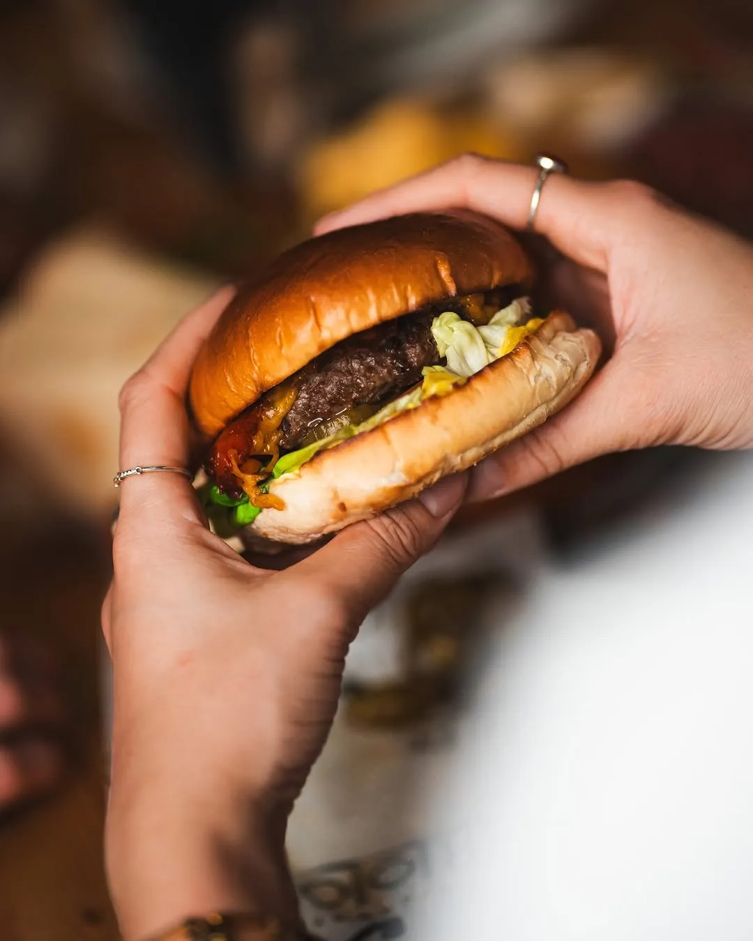 A close-up, professionally taken photo of a burger being held by hands.