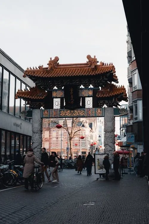 The image effectively captures a Chinese gate in a street scene, demonstrating good composition and photo-realistic qualities. The gate itself is sharp and the colors are accurate for the overcast lighting conditions. However, the flat lighting prevents a more dynamic feel.