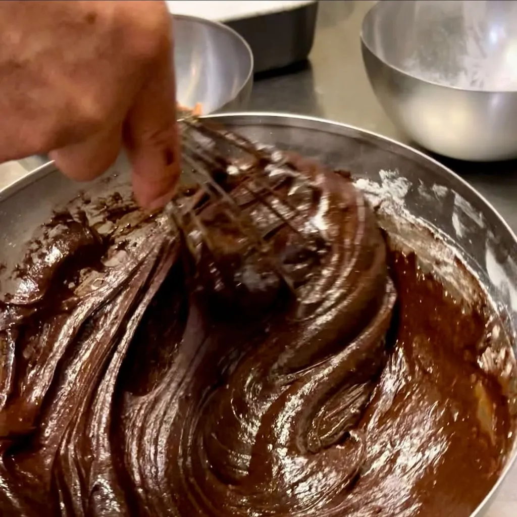 The image effectively captures the rich texture and glossy appearance of chocolate batter, benefiting from excellent photo-realism and sharp focus on the key elements. The composition is strong, drawing attention to the dynamic swirls of the batter. While generally well-lit, some of the darker areas could benefit from slightly more illumination to reveal further detail.