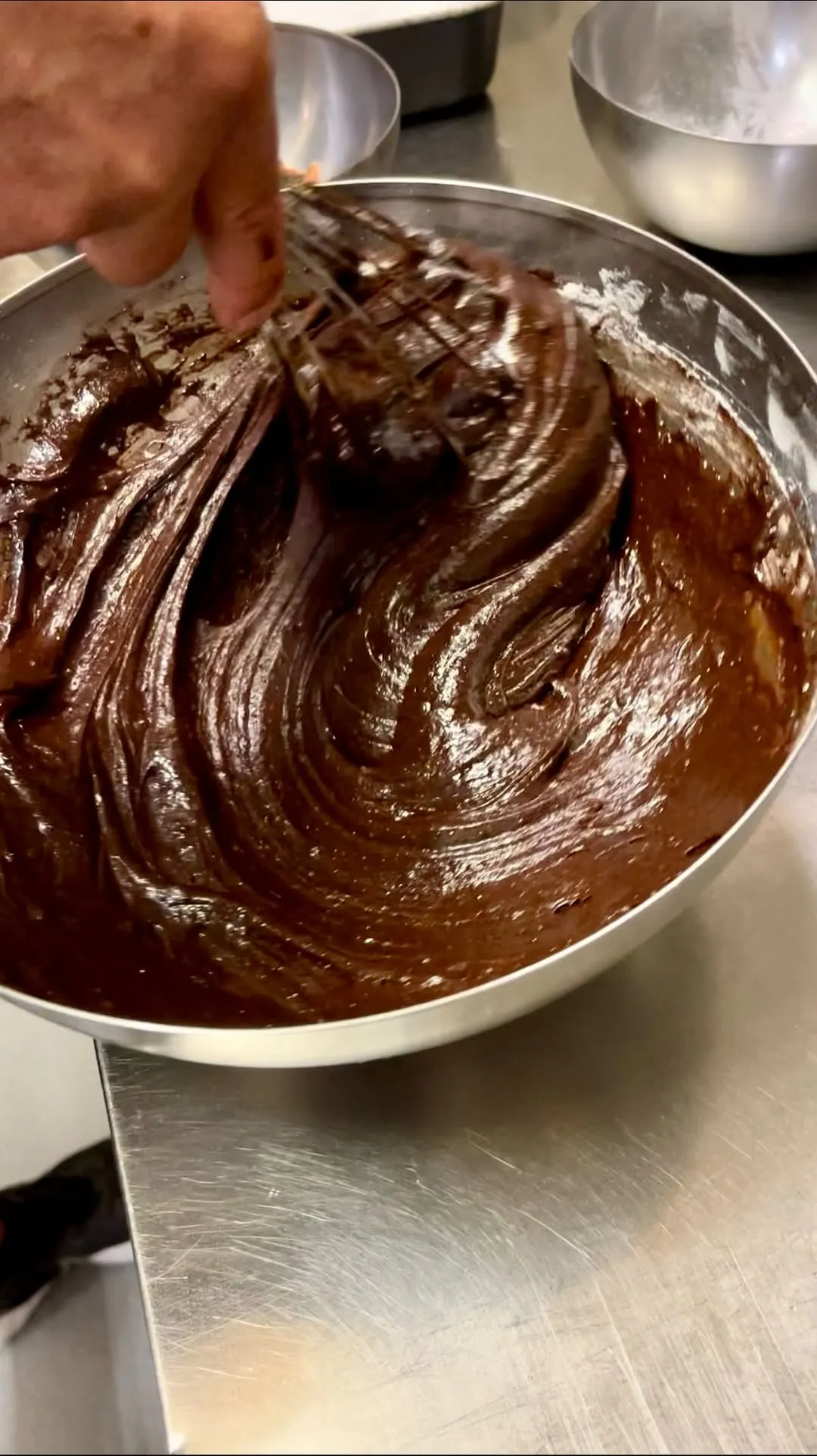 The image effectively captures the rich texture and glossy appearance of chocolate batter, benefiting from excellent photo-realism and sharp focus on the key elements. The composition is strong, drawing attention to the dynamic swirls of the batter. While generally well-lit, some of the darker areas could benefit from slightly more illumination to reveal further detail.