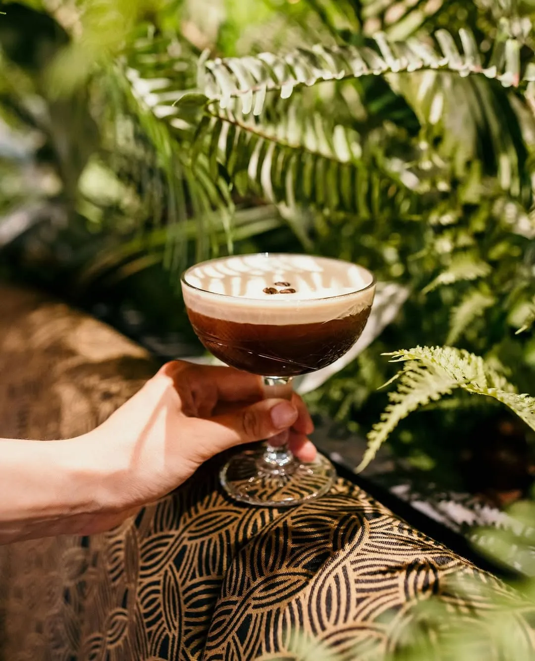 A well-composed and aesthetically pleasing image featuring a cocktail. The drink is full and professionally presented, with excellent natural lighting that highlights its texture and garnishes. The sharpness of the main subject and the pleasing bokeh in the background contribute to a high-quality, photo-realistic result. The colors are vibrant and accurate, creating an inviting visual.