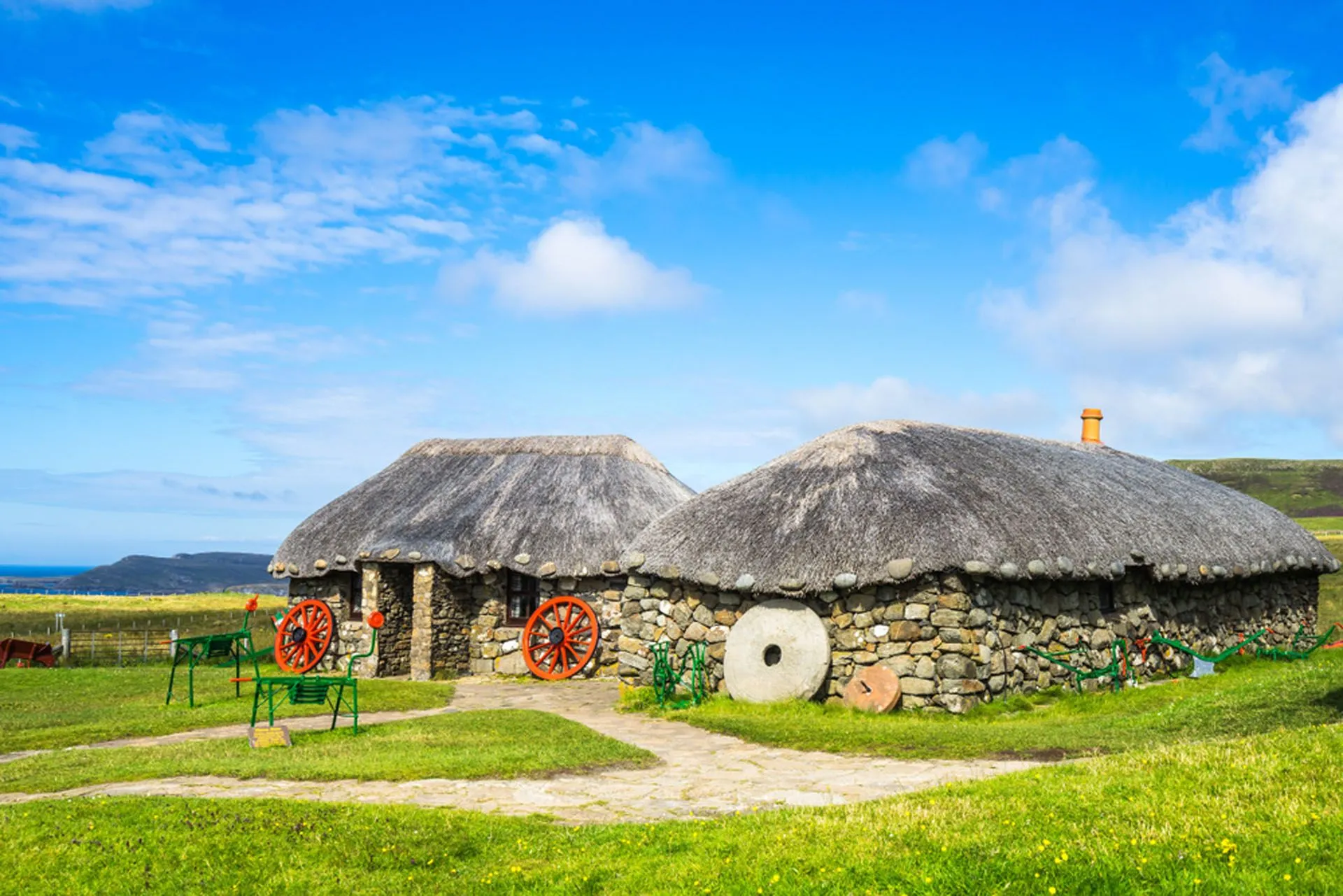 An exemplary photograph of traditional thatched-roof cottages, showcasing excellent composition, vibrant colors, and sharp focus. The natural lighting enhances the detail and texture of the stone walls and thatch. It captures a serene rural scene with historical architectural elements.