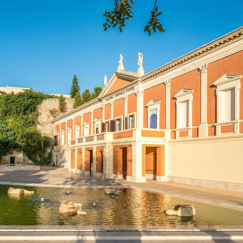 An outdoor shot of a historic building with classical architectural elements, featuring a large courtyard and a decorative fountain in the foreground. The image is well-composed, brightly lit by natural sunlight, and exhibits strong photorealism. The colors are vibrant and accurate, and the key elements, including the building and fountain, are sharp and in focus. The blue sky provides a clear backdrop.