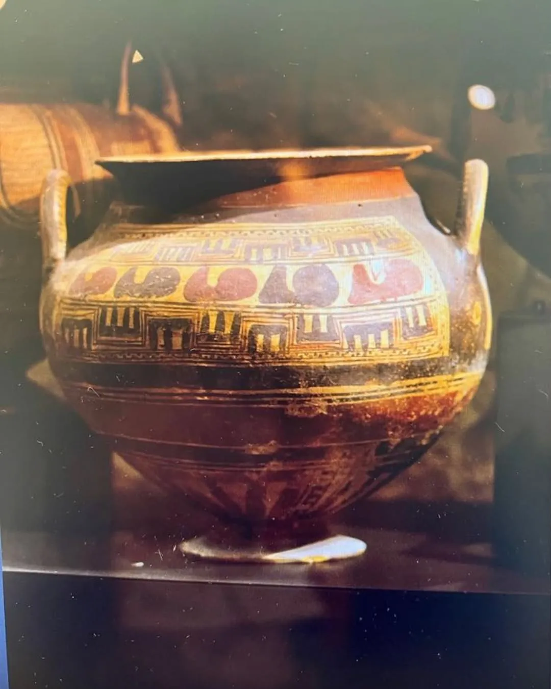 An ancient pottery vessel, likely a krater, adorned with geometric and stylized patterns, captured with dramatic lighting.