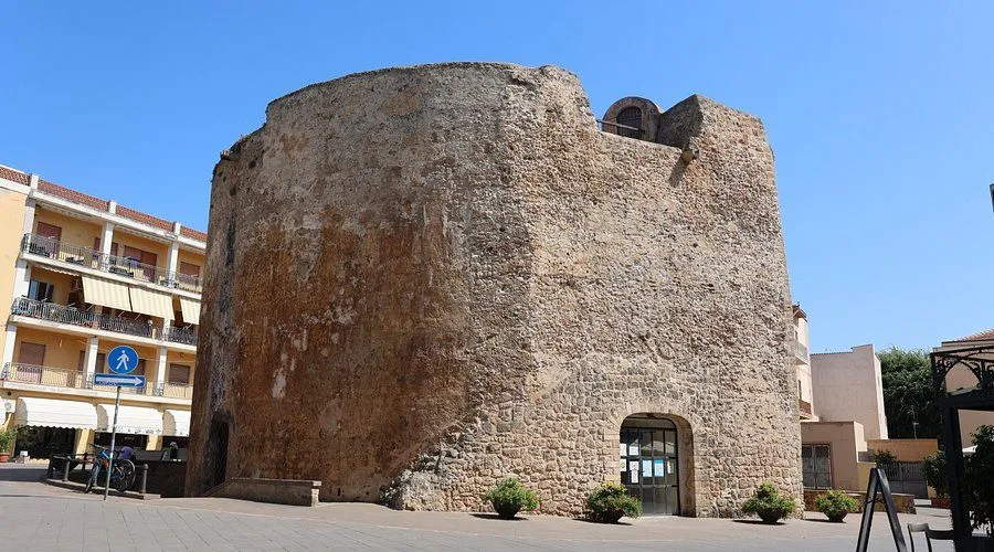 A clear, well-composed photograph of an old stone building or tower under a bright blue sky.